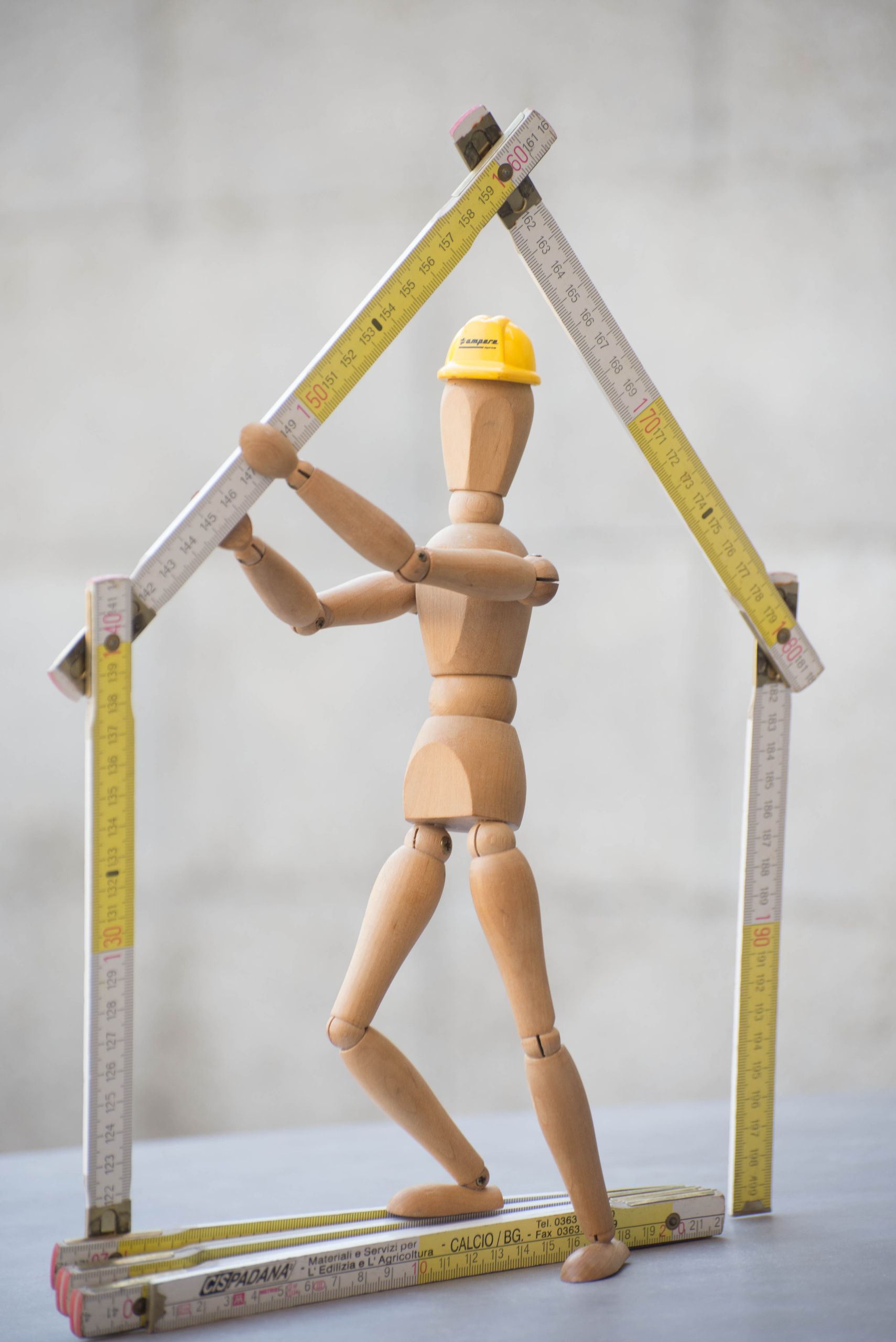 Artistic representation of a construction theme using a wooden mannequin and folding rulers.