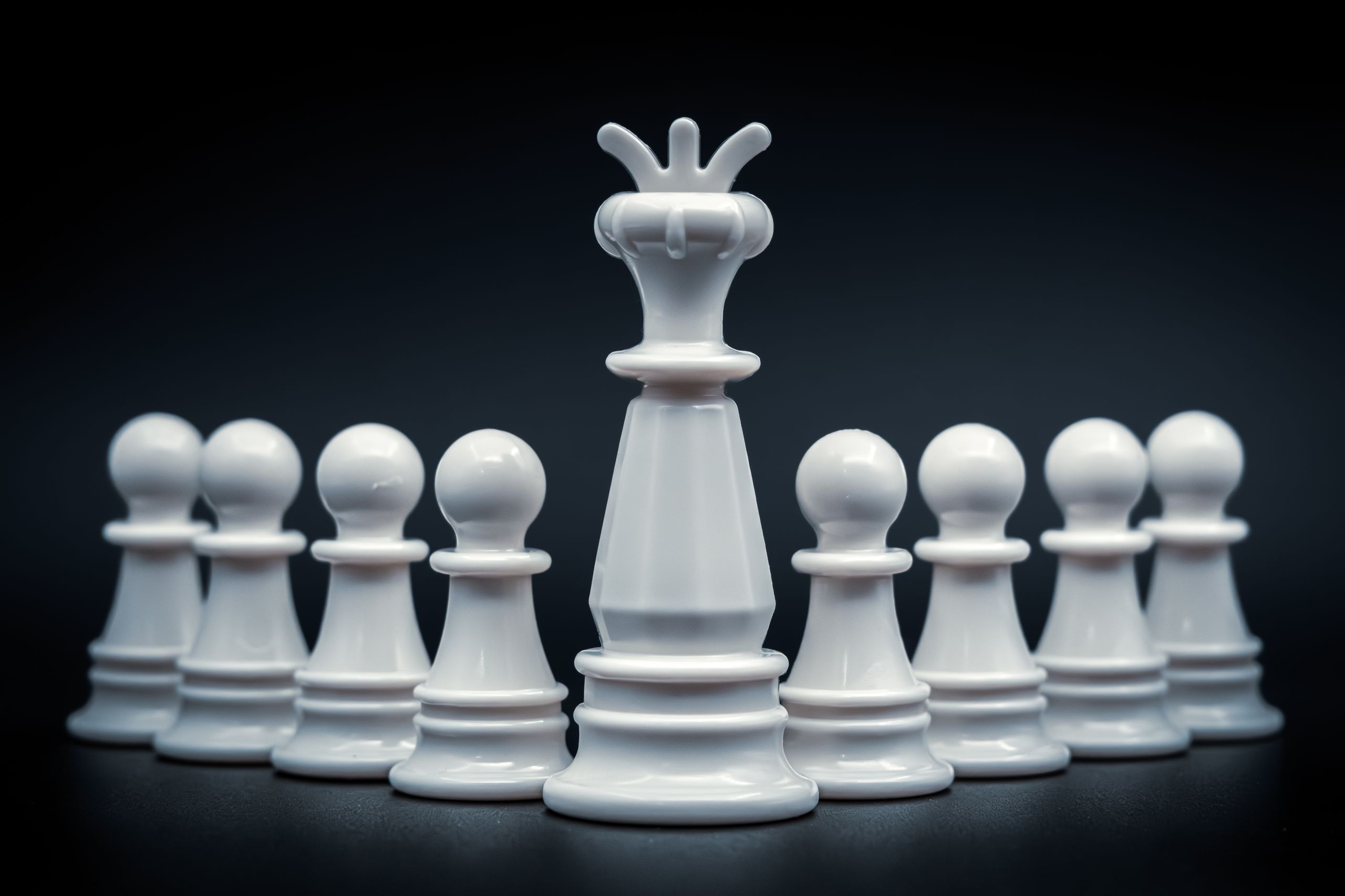 Close-up of white king and pawns on chessboard, symbolizing leadership and strategy.